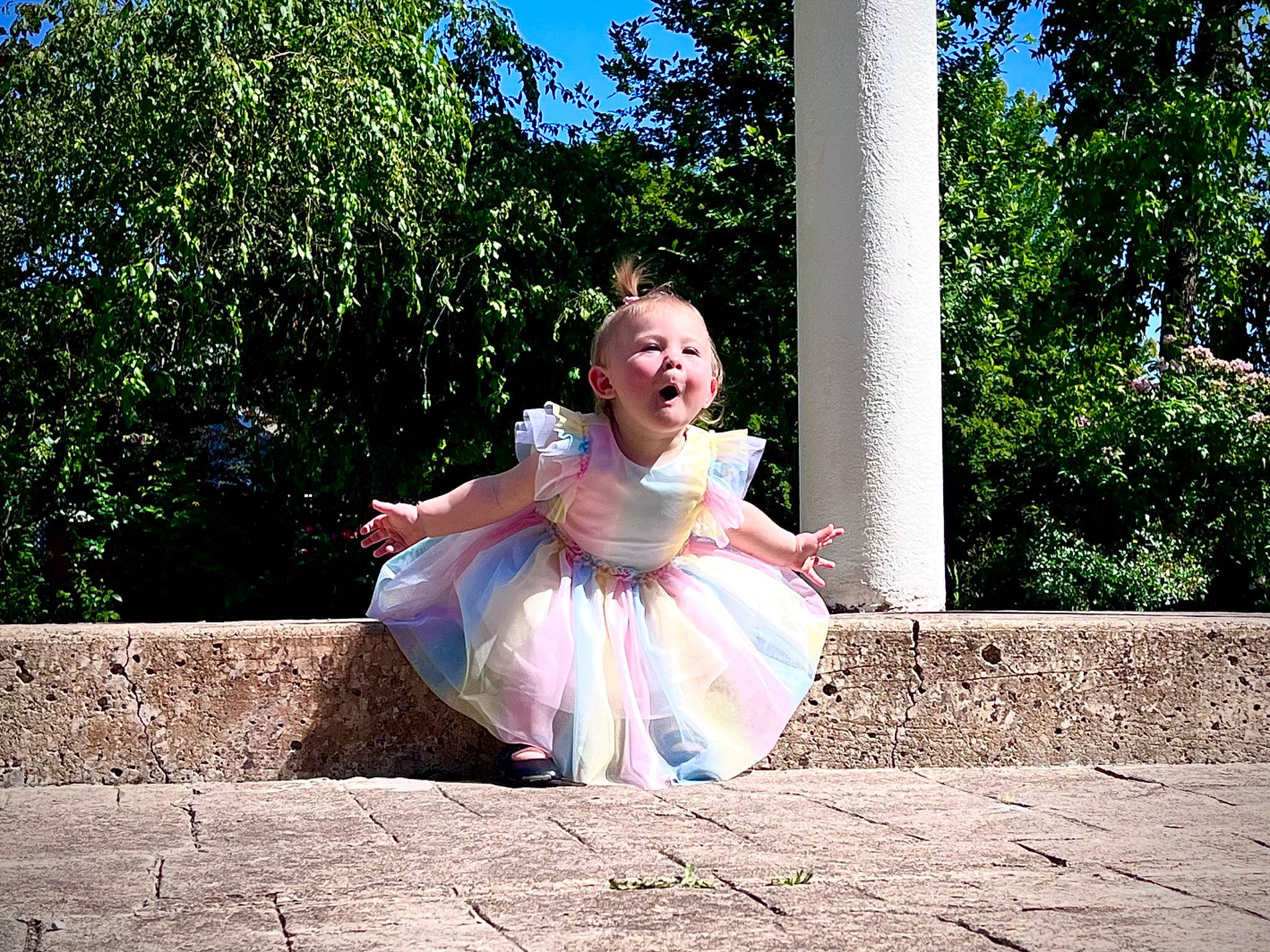 Kiara is registered to the contest to win money with this photo: bridal_party_dress, child, costume, fun, garden, grass, happy, leisure, magenta, people_in_nature, person, photo_shoot, pink, plant, portrait_photography, recreation, sitting, sky, toddler, tree