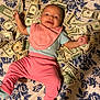 Samantha joined the competition — help win amazing prizes! baby, infant, money, dollar_bills, pink_clothing, blue_clothing, bib, smiling, lying_down, bedspread, floral_pattern, happy, person, indoors, currency, cash, cute, child, finance, playful