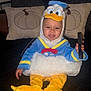 Adonis joined the competition — help win amazing prizes! baby, blue, child, costume, couch, cute, donald_duck, face, happy, headwear, indoor, person, pillows, plush, pumpkin, remote_control, sitting, smiling, white, yellow