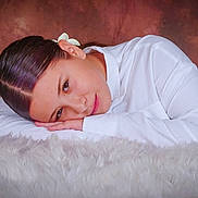 Léa participe au concours pour gagner de l'argent avec cette photo : brown_background, calm, casual, child, close_up, expression, face, fluffy_surface, hair_clip, hands, indoor, peaceful, portrait, relaxed, resting, skin, soft_lighting, studio, white_shirt, young_person