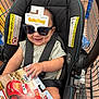 baby, car_seat, shopping_cart, sunglasses, toy, packaging, smile, child, infant, seatbelt, store, retail, plastic, hand, clothing, person, happy, indoor, product, cart