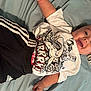 baby, child, smiling, tshirt, graphic_tshirt, shorts, adidas, bed, blanket, happy, infant, person, clothing, casual, laying_down, cute, indoor, comfortable, young, smile