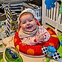 baby, smiling, infant, baby_seat, toy, colorful, indoor, child, happy, clothing, face, play, activity_center, seat, hand, expression, cute, cheerful, home, young