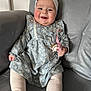 Megan is registered to the contest to win money with this photo: baby, smiling, pacifier, headband, bow, blue_dress, floral_pattern, white_tights, sitting, couch, gray_couch, happy, child, indoors, cheerful, cute, infant, portrait, person, comfort