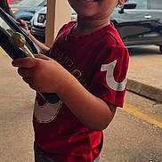 Kemarion joined the competition — help win amazing prizes! child, toddler, smiling, red_shirt, outdoor, parking_lot, car, concrete, person, curly_hair, holding, side_view, urban, daylight, casual_clothing, screenshot, social_media, video, user_interface, happy
