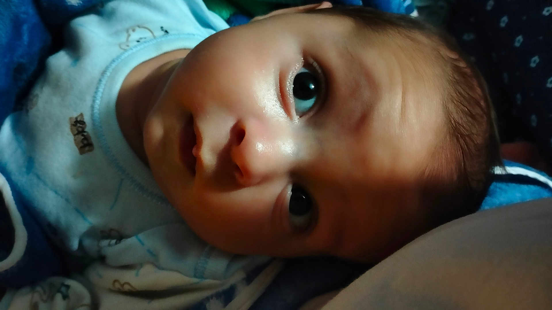 Mohamed is registered to the contest to win money with this photo: baby, close_up, face, infant, newborn, blanket, blue_clothing, eyes, head, skin, cute, lying_down, portrait, sleepwear, soft, indoors, person, child, baby_garment, young
