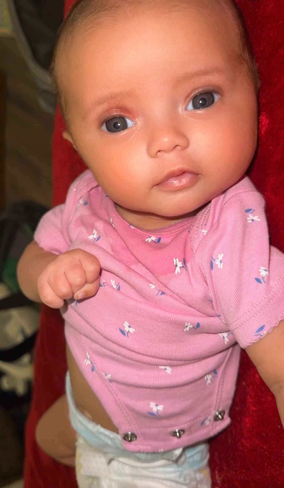 Zuriiaunna joined the competition — help win amazing prizes! baby, infant, child, pink_clothing, onesie, cute, face, eyes, hand, skin, diaper, lying_down, portrait, soft_texture, red_background, small_child, newborn, expression, looking_at_camera, human