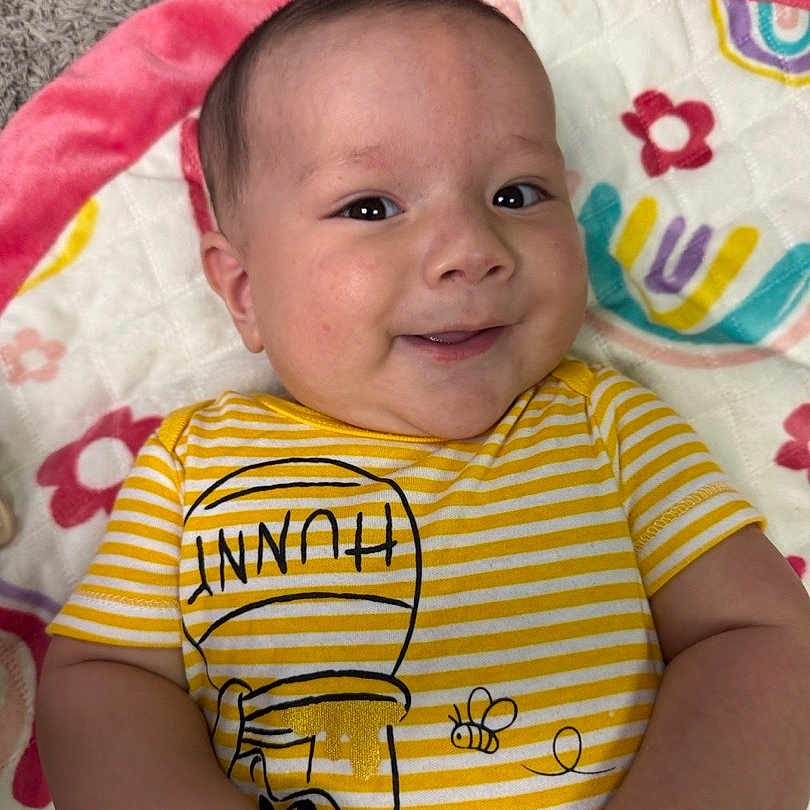 Nikolas joined the competition — help win amazing prizes! baby, smiling, infant, striped_shirt, yellow, honey_pot, bee, blanket, floral_pattern, cute, happy, lying_down, child, portrait, indoors, skin, face, arms, clothing, young