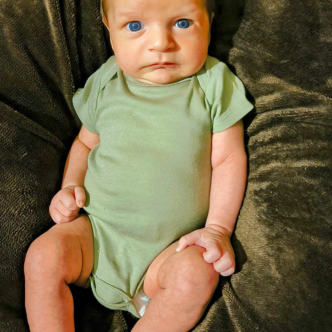 Oliver is registered to the contest to win money with this photo: baby, baby_clothing, blue_eyes, child, cute, foot, hand, human, indoors, infant, newborn, onesie, plush_blanket, portrait, relaxed, serious_expression, sitting, skin, soft_texture, young_child