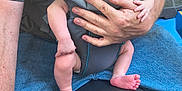 Oliver joined the competition — help win amazing prizes! baby, baby_carrier, adult, hand, gray_tshirt, blue_jeans, blue_vehicle, seat, sleeping, skin, person, outdoor, foot, arm, clothing, hand_holding, transport, comfort, rest, closeup