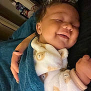 Kyler is registered to the contest to win money with this photo: baby, smiling, blanket, onesie, bear_pattern, sleeping, closeup, indoor, hand, person, cozy, child, cute, soft, warm, resting, peaceful, portrait, infant, comfort