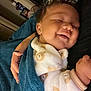 baby, smiling, blanket, onesie, bear_pattern, sleeping, closeup, indoor, hand, person, cozy, child, cute, soft, warm, resting, peaceful, portrait, infant, comfort