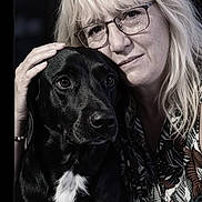 Jack a rejoint le concours — aidez-le/la à gagner de superbes lots ! affection, animal, black_dog, calm, close_up, companionship, dog, face, glasses, hand, human, indoor, intimacy, long_hair, love, patterned_shirt, pet, portrait, white_chest_patch, woman