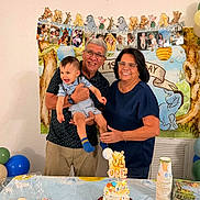 Javier is registered to the contest to win money with this photo: child, toddler, adult, grandparents, birthday_cake, cupcakes, party, celebration, balloons, table, glasses, smile, happy, decorations, banner, indoor, family, holding, food, winnie_the_pooh