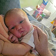 Colbee is registered to the contest to win money with this photo: baby, infant, hand, towel, resting, closeup, indoor, person, freckles, skin, table, water_bottle, cans, background, soft, comfort, home, white_clothing, face, expression