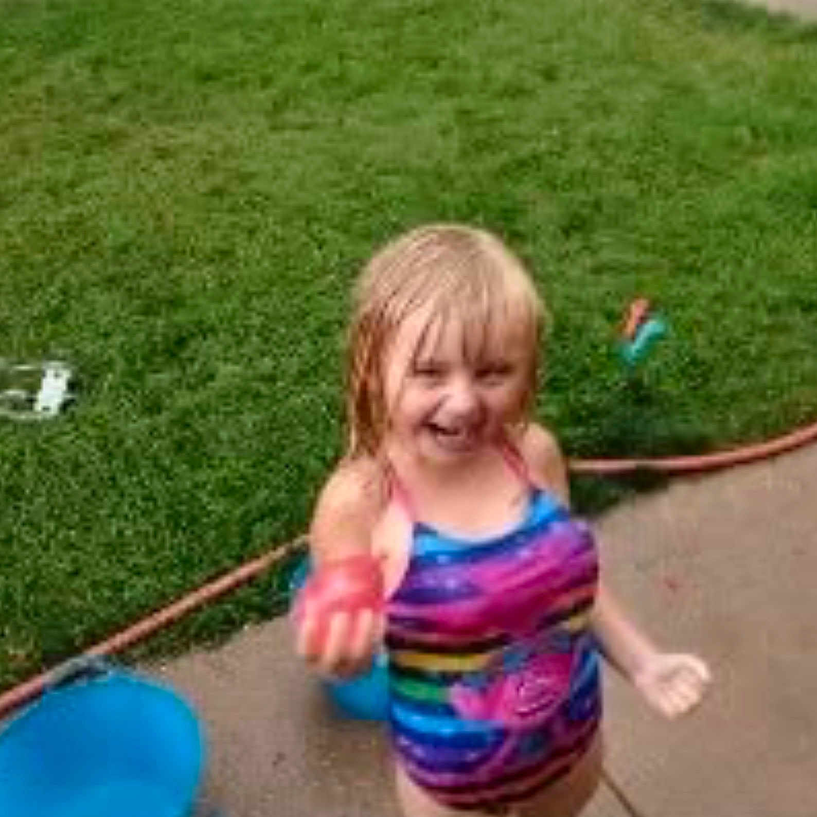 Aubryana is registered to the contest to win money with this photo: child, girl, swimsuit, colorful_clothing, water_play, outdoor, grass, bucket, sidewalk, wet_surface, summer, fun, smiling, blond_hair, playful, water_toy, happy, young, person, daylight