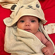 Emy a rejoint le concours — aidez-le/la à gagner de superbes lots ! baby, towel, hood, infant, wrapped, cute, red_background, face, hand, skin, eyes, blanket, clothing, expression, portrait, newborn, soft, child, lying_down, indoor