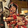 man, dog, indoor, plaid, hoodie, beanie, smile, pet, holding, kitchen, cabinet, wall_decor, butterfly, casual, clothing, happy, portrait, brown_dog, matching_outfits, home