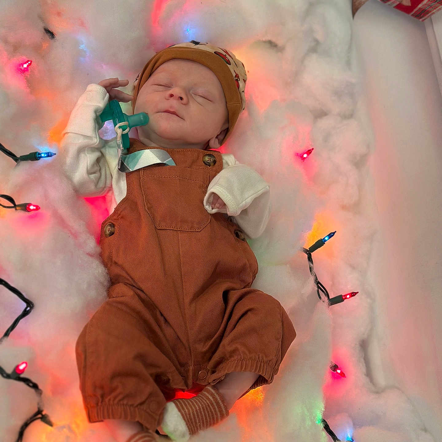 Dallas is registered to the contest to win money with this photo: baby, christmas_lights, cotton, cozy, cute, decorations, festive, hat, holiday, indoors, infant, newborn, overalls, peaceful, portrait, resting, sleeping, socks, soft, warm