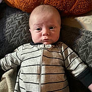 Dallas is registered to the contest to win money with this photo: baby, infant, child, face, blanket, cushion, striped_clothing, onesie, soft_lighting, indoor, portrait, cute, newborn, young_child, expression, resting, comfort, cozy, head, person