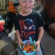 Karson is registered to the contest to win money with this photo: child, boy, smiling, indoor, bucket, candy, colorful, clothing, tshirt, kneeling, carpet, furniture, room, toy, happy, person, casual, home, spiderman, young
