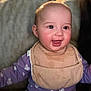 Macie is registered to the contest to win money with this photo: baby, smiling, bib, purple_clothing, indoor, child, happy, face, person, cute, infant, sitting, home, cozy, young_child, portrait, cheerful, reaching, apparel, head