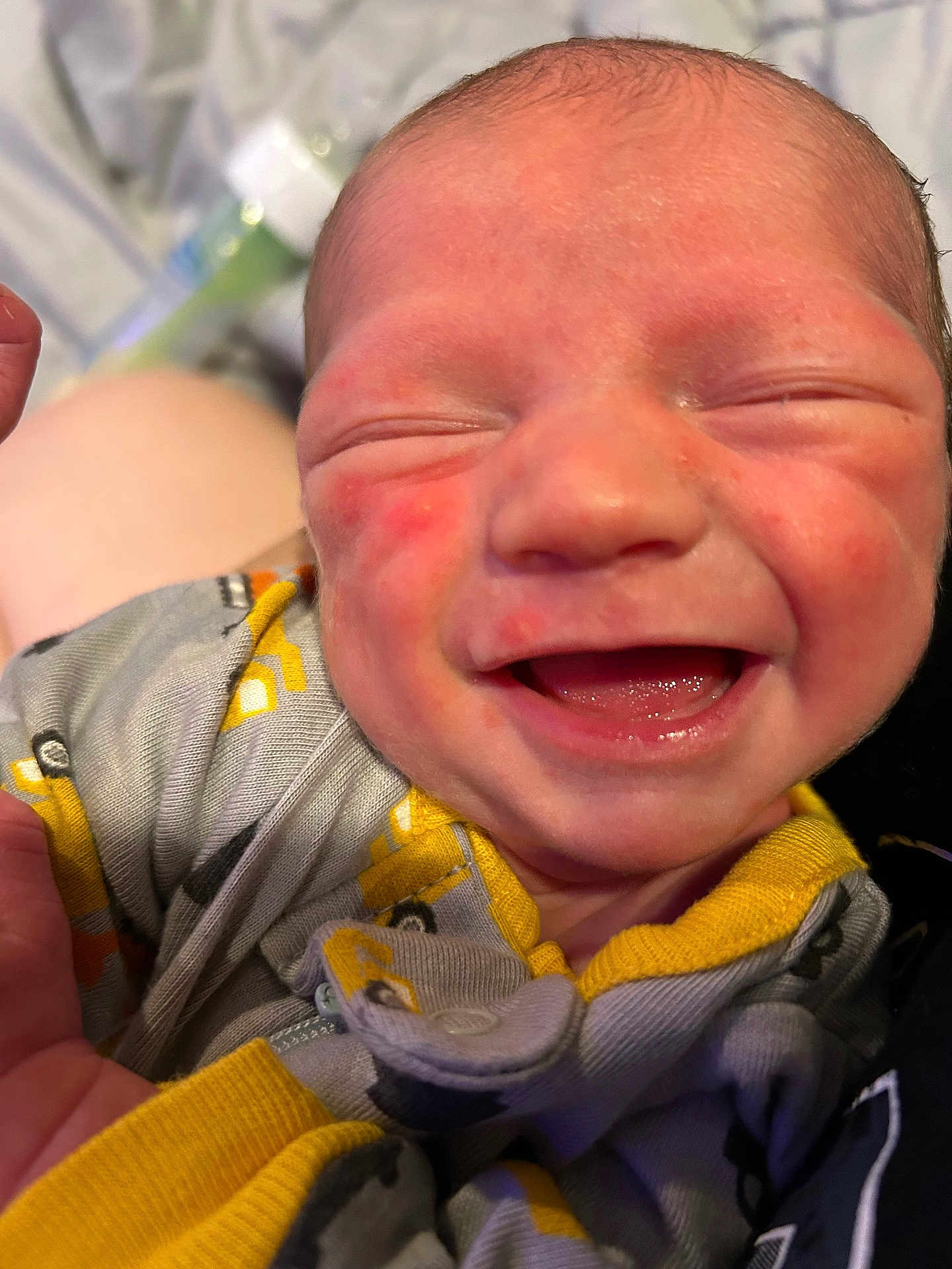 Hudson is registered to the contest to win money with this photo: newborn, baby, smiling, face, infant, clothing, yellow, grey, onesie, happy, closeup, person, skin, hand, cute, young, child, expression, joy, portrait