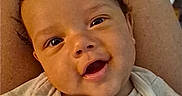 Roman is registered to the contest to win money with this photo: baby, smiling, child, face, person, clothing, cute, happy, infant, portrait, toddler, skin, eyes, mouth, hand, sitting, legs, indoors, shirt, animal_print