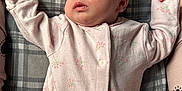 Hazel is registered to the contest to win money with this photo: baby, sleeping, infant, onesie, pink_clothing, floral_pattern, plaid_blanket, peaceful, face, closed_eyes, newborn, soft_fabric, hands_up, resting, cozy, cute, child, lying_down, indoors, portrait