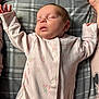 baby, sleeping, infant, onesie, pink_clothing, floral_pattern, plaid_blanket, peaceful, face, closed_eyes, newborn, soft_fabric, hands_up, resting, cozy, cute, child, lying_down, indoors, portrait