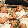 baby, infant, holding_hands, blanket, bed, diaper, clothing, person, indoor, couch, remote_control, legs, relaxation, skin, cute, toddler, child, home, family, resting