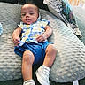 My'Drevious Bell is registered to the contest to win money with this photo: baby, infant, child, pillow, couch, clothing, blue_shorts, white_sneakers, checkered_shirt, indoor, living_room, colorful_pillow, wooden_stool, relaxed, portrait, person, young_child, comfort, casual, home