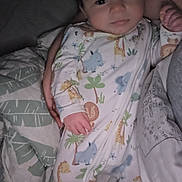 Tatum is registered to the contest to win money with this photo: baby, infant, onesie, animal_print, bed, blanket, adult_hand, sleepwear, cozy, portrait, face, person, indoor, sleep, cuddle, parent, child, cute, comfort, rest