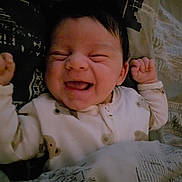 Tatum joined the competition — help win amazing prizes! baby, blanket, child, cozy, cute, dark_hair, expression, face, happy, indoors, infant, newborn, patterned_blanket, person, portrait, raised_hands, sleeping_area, sleepwear, smiling, young