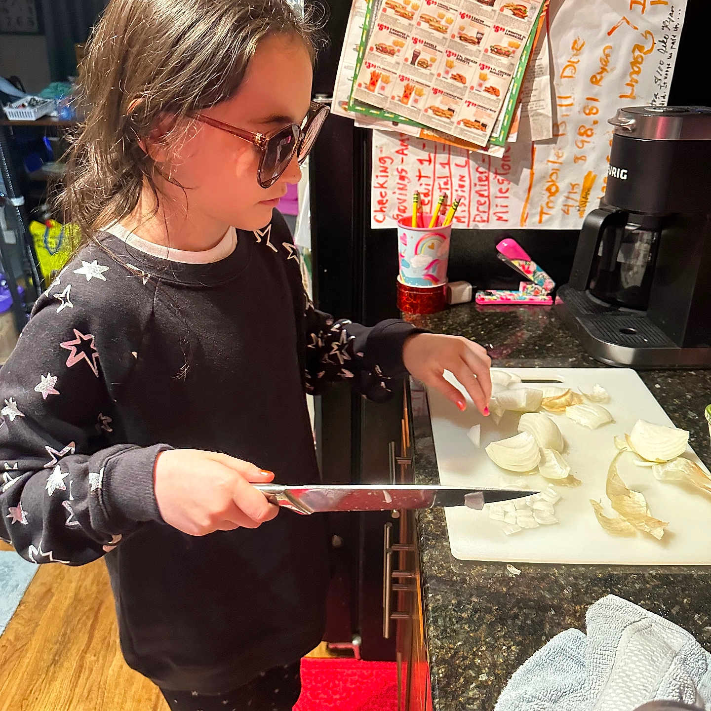 Lindsay joined the competition — help win amazing prizes! can, child, coffee_maker, countertop, cup, cutting_board, floor, fridge, glasses, indoor, kitchen, knife, leggings, notes, onion, pencils, red_rug, stapler, sweatshirt, towel
