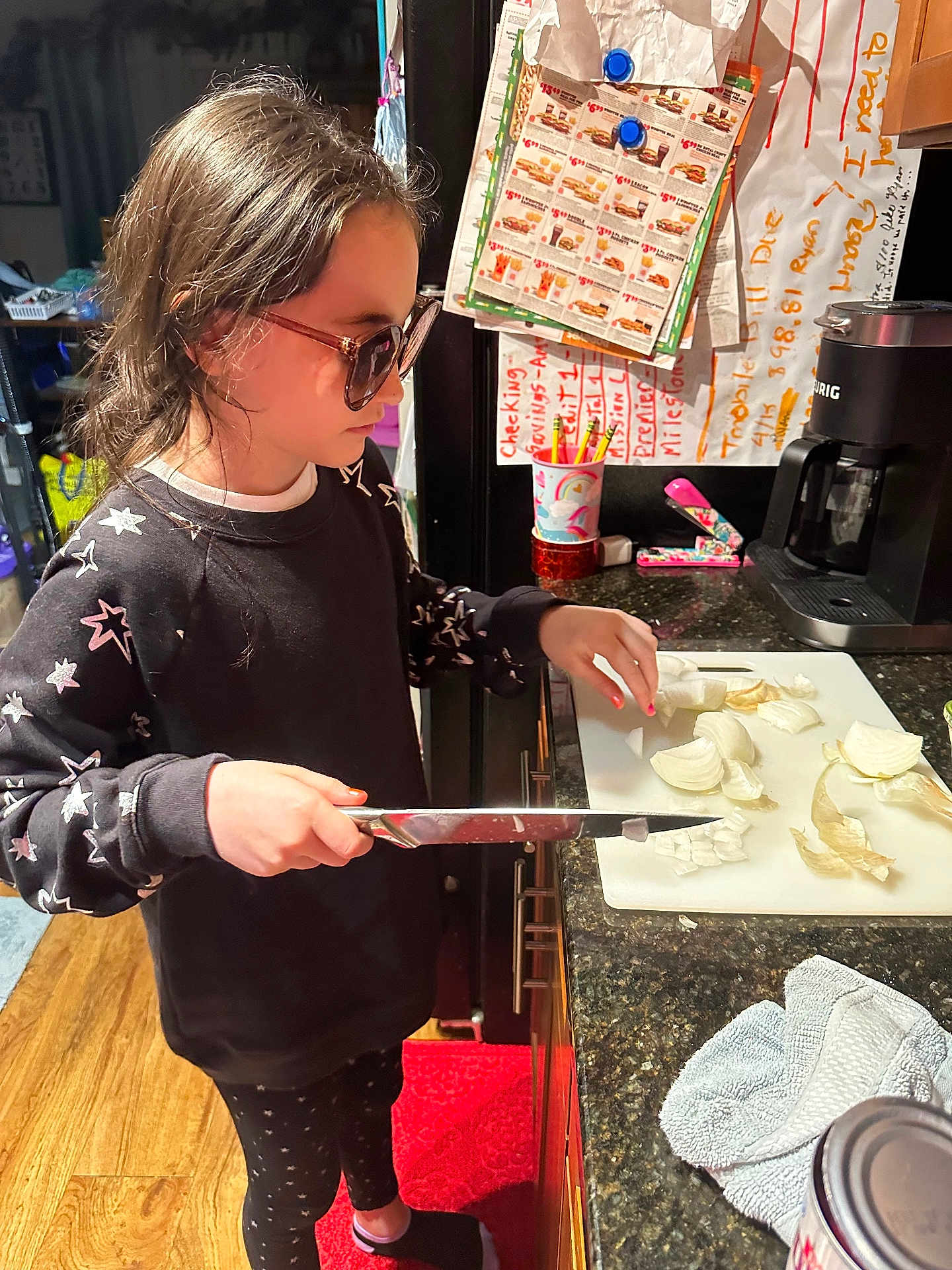 Lindsay joined the competition — help win amazing prizes! can, child, coffee_maker, countertop, cup, cutting_board, floor, fridge, glasses, indoor, kitchen, knife, leggings, notes, onion, pencils, red_rug, stapler, sweatshirt, towel