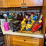 Nicky is registered to the contest to win money with this photo: cat, kitchen, countertop, chips, food, bags, utensils, knives, cutting_board, cabinet, wooden_cabinet, gray_cat, pet, indoor, curious, table, container, pink_thermos, appliance, tiled_wall