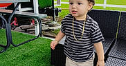 Enzo Calero Cepeda joined the competition — help win amazing prizes! backyard, building, chair, child, curly_hair, daylight, fence, furniture, gold_chain, grass, outdoor, patio, playful, portrait, shoes, shorts, standing, striped_shirt, table, toddler