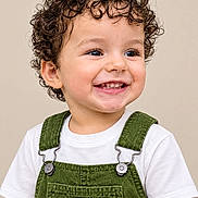 Enzo Calero Cepeda joined the competition — help win amazing prizes! toddler, child, curly_hair, smiling, teeth, portrait, studio, close_up, overalls, green_clothing, white_shirt, happy, face, eyes, hair, baby, person, indoor, beige_background, fashion