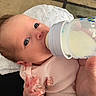 baby, infant, bottle, milk, feeding, hand, clothing, pink_outfit, carpet, floor, person, face, eyes, newborn, skin, baby_fashion, baby_hand, closeup, indoor, feeding_time