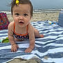 Quinn is registered to the contest to win money with this photo: baby, child, beach, sand, towel, swimsuit, bow, hair_accessory, ocean, waves, cloudy_sky, crawling, curious, outdoor, summer, striped_towel, colorful, infant, barefoot, playful