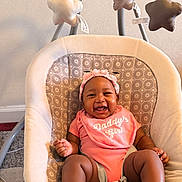 Mirha joined the competition — help win amazing prizes! baby, infant, smiling, pink_clothing, headband, baby_seat, cushion, patterned_fabric, star_toys, mobile, indoor, carpet, happy, child, cute, baby_bib, baby_girl, playful, seated, comfort
