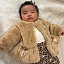 baby, fur_coat, leopard_print, leggings, blanket, infant, cute, fashion, portrait, child, soft_texture, warm_clothing, indoor, laying_down, toddler, face, head, expression, bow, plush