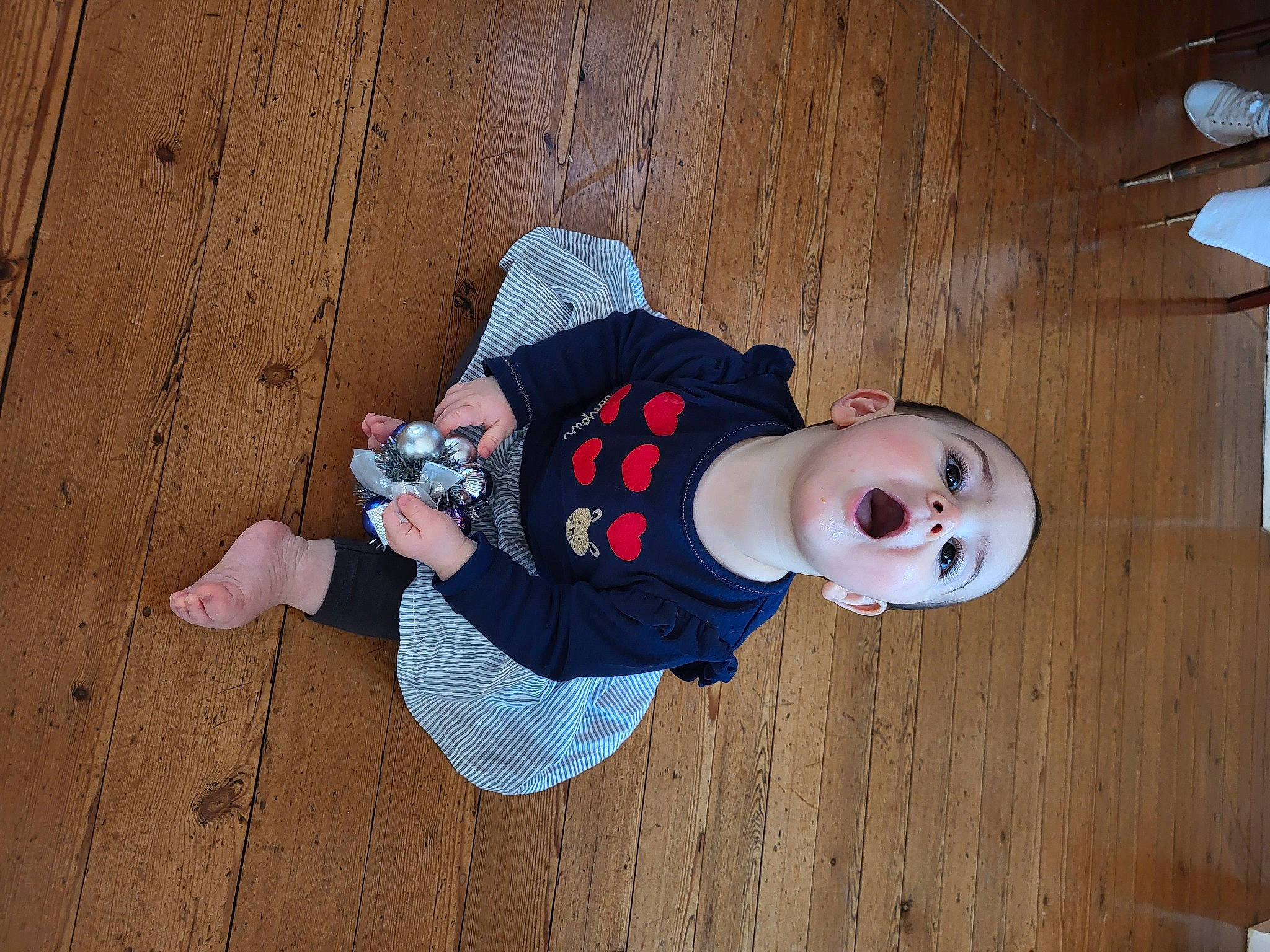 Astrid a rejoint le concours — aidez-le/la à gagner de superbes lots ! baby, baby_toddler_clothing, ceiling_fan, child, costume, floor, flooring, fun, happy, hardwood, hat, headgear, human_leg, pattern, person, plywood, sitting, sleeve, toddler, wood