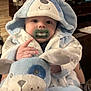 Dean joined the competition — help win amazing prizes! baby, pacifier, plush_toy, blue_robes, hood, indoor, soft_toy, child, cute, infant, smiling, face, hand, animal_theme, person, warm_clothing, cozy, portrait, young_child, seated