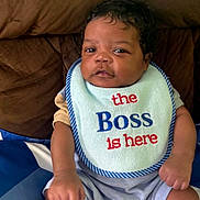 Blake joined the competition — help win amazing prizes! baby, infant, bib, clothing, face, person, sitting, blanket, cushion, indoor, cute, child, young, expression, sock, pattern, text, blue, brown, portrait