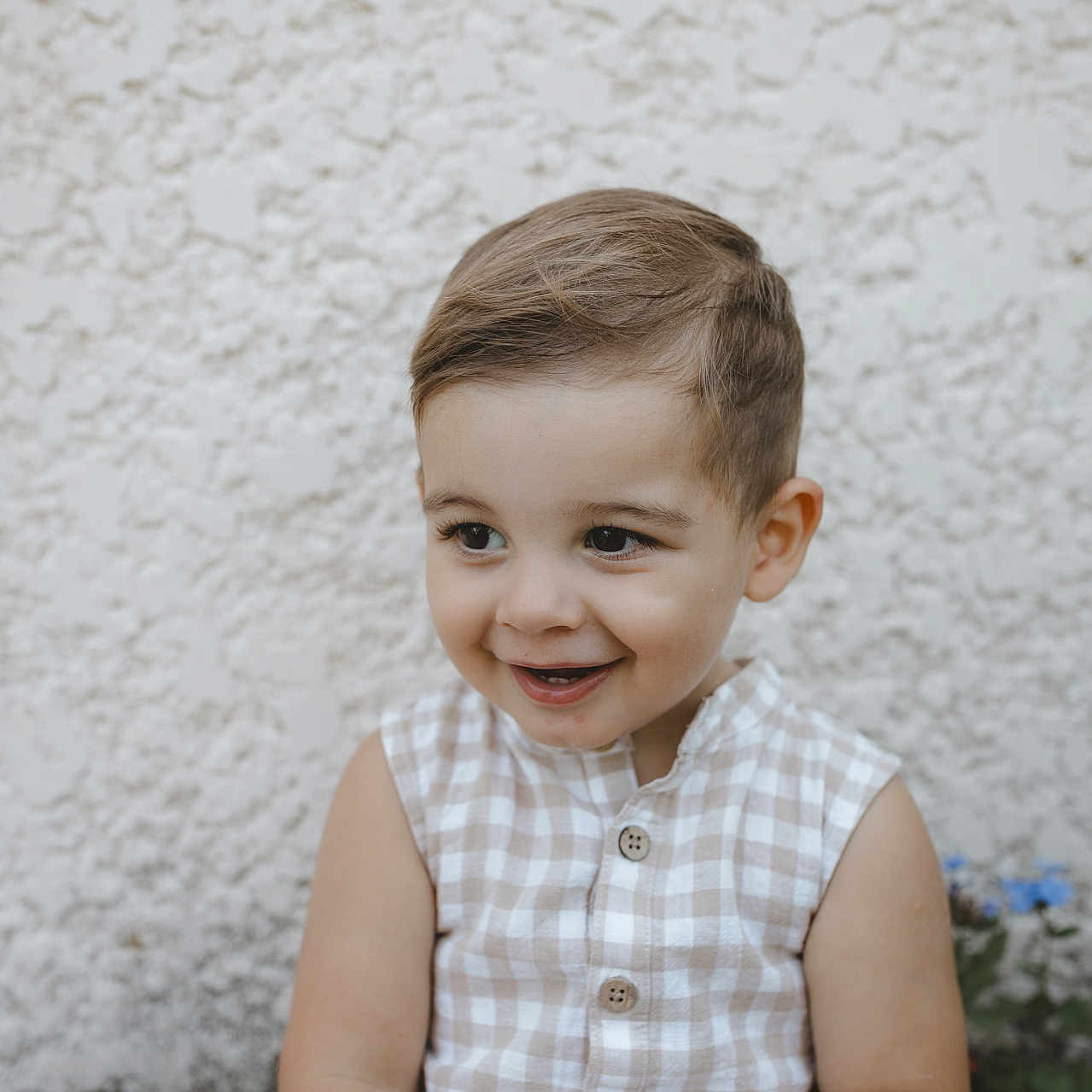 Felix participe au concours pour gagner de l'argent avec cette photo : beige, buttoned, checkered, child, clothing, cute, face, hair, happy, outdoor, person, portrait, seated, skin, sleeveless, smile, texture, toddler, wall, white