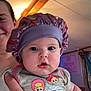 Breanna is registered to the contest to win money with this photo: baby, child, person, indoor, purple_bonnet, toy_story, shirt, smiling_adult, hand, arm, wooden_beam, ceiling, poster, wall, face, clothing, holding, expression, cute, infant
