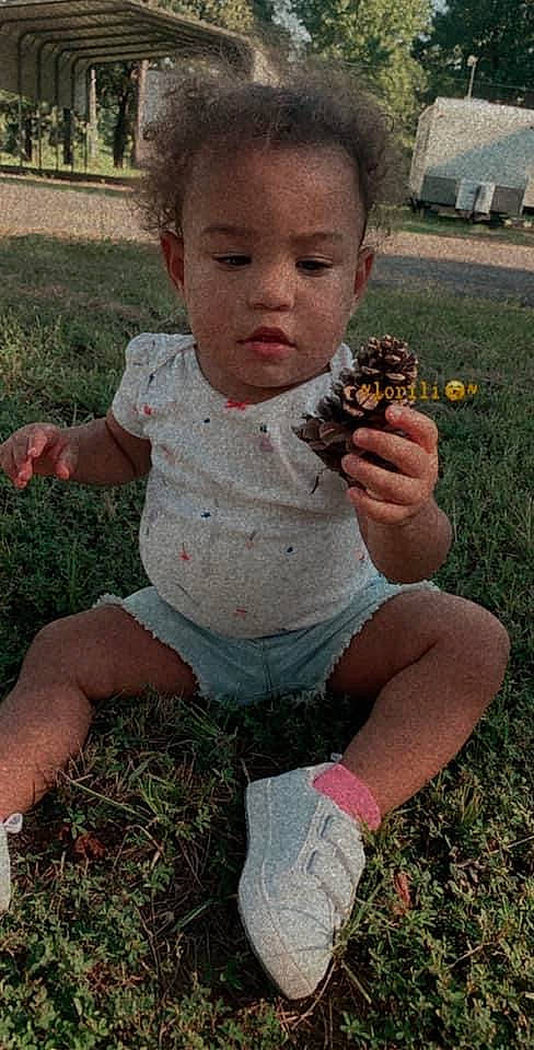Gianna-grace is registered to the contest to win money with this photo: baby_toddler_clothing, botany, child, finger, food, fruit, grass, grass_family, hand, happy, head, lawn, leaf, people_in_nature, person, plant, sitting, soil, thumb, toddler
