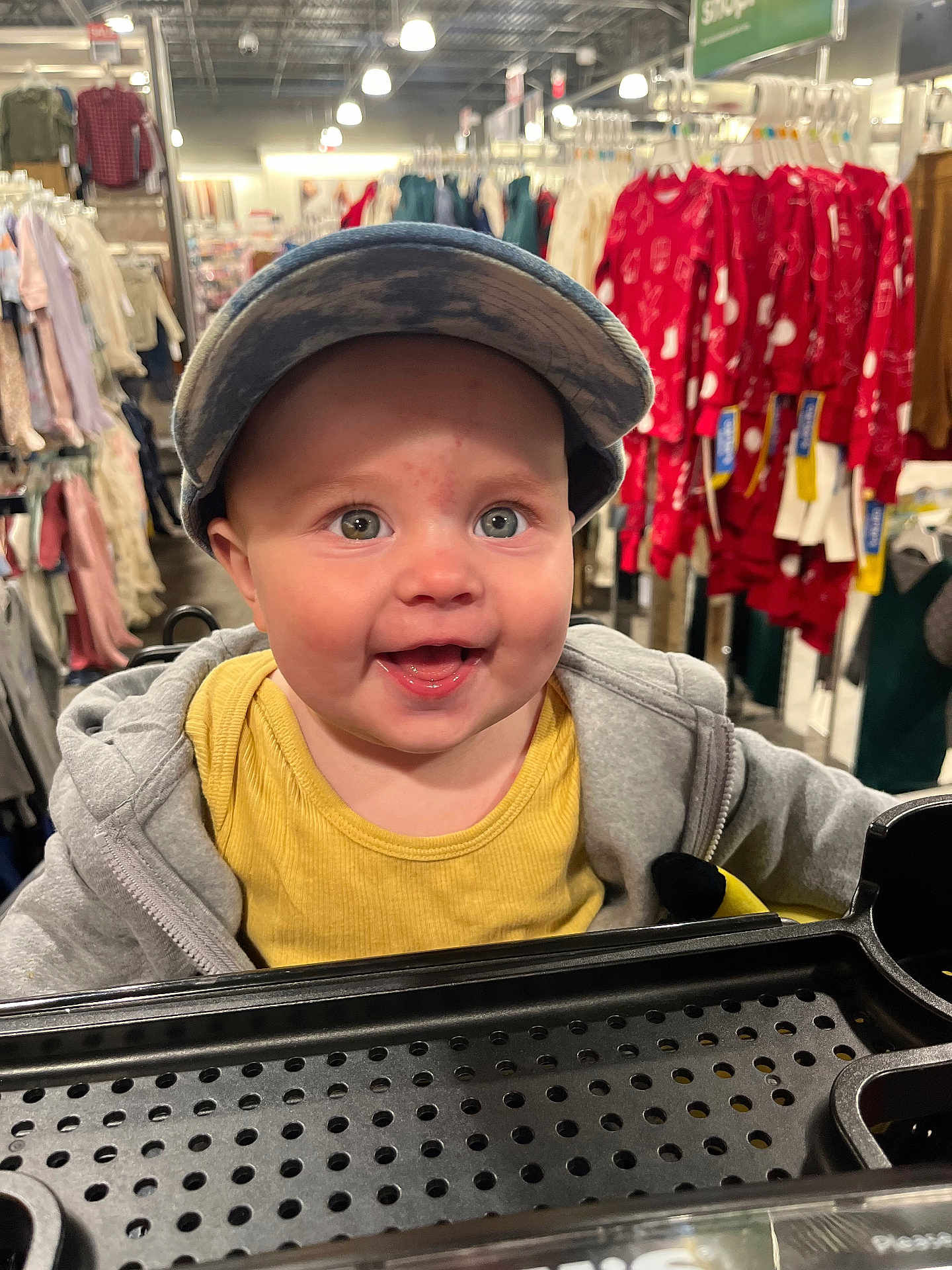 Ryatt joined the competition — help win amazing prizes! baby, child, shopping_cart, cap, smile, clothing_store, jacket, yellow_shirt, rack, shopping, happy, face, retail, apparel, infant, store_interior, cute, person, headwear, casual_wear